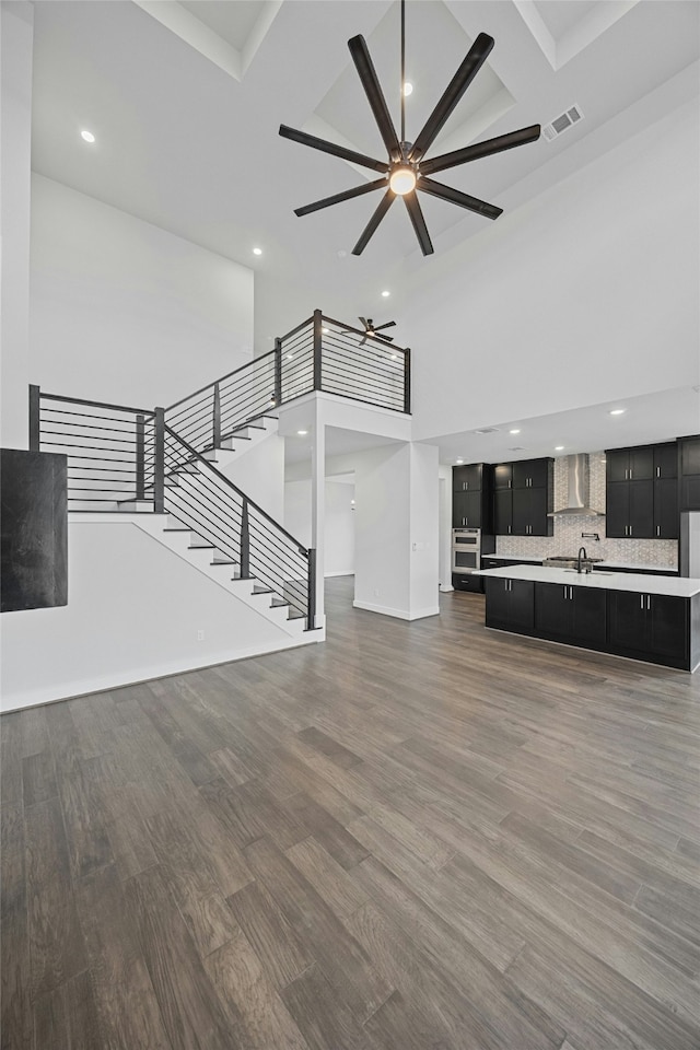 unfurnished living room featuring coffered ceiling, sink, a towering ceiling, ceiling fan, and hardwood / wood-style floors