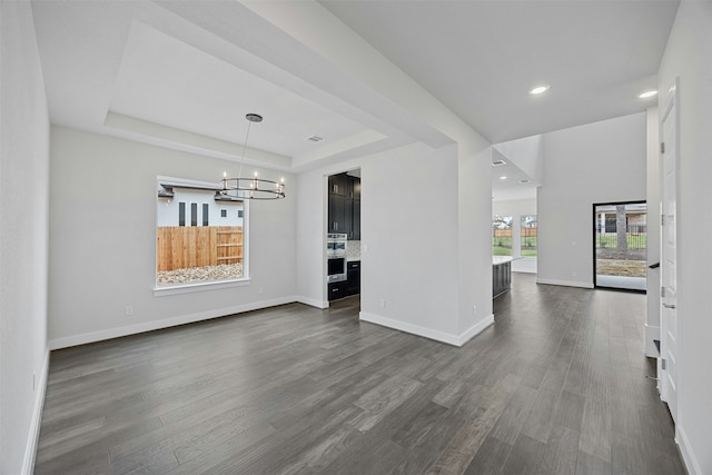 interior space featuring dark wood-type flooring, an inviting chandelier, and a tray ceiling