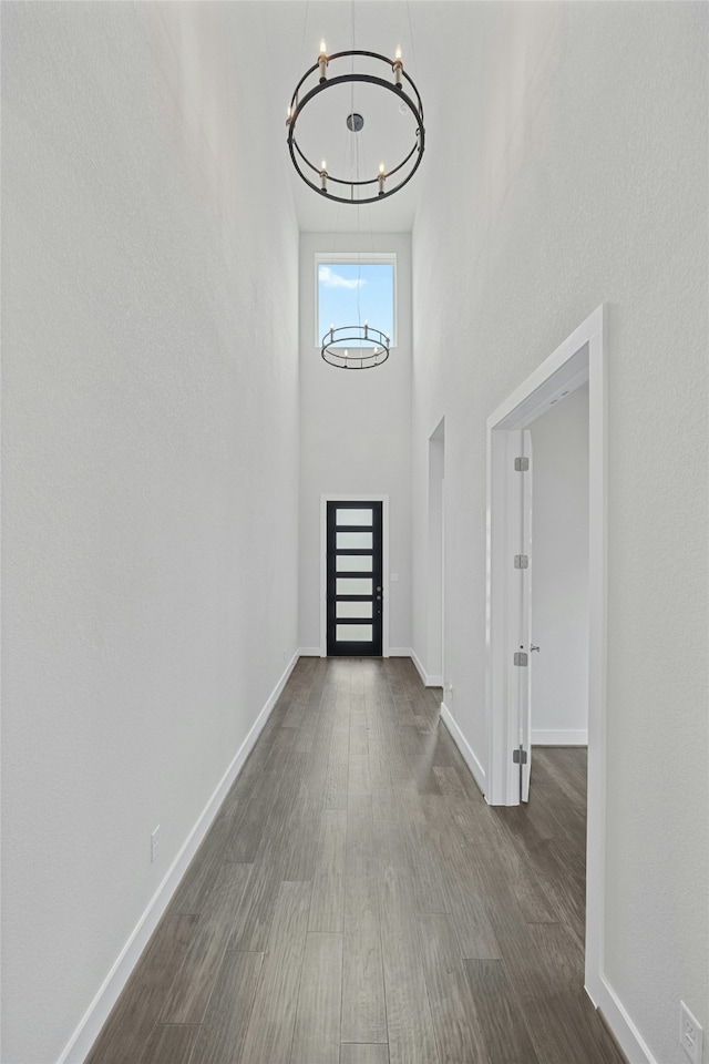 entryway featuring a towering ceiling, dark wood-type flooring, and an inviting chandelier