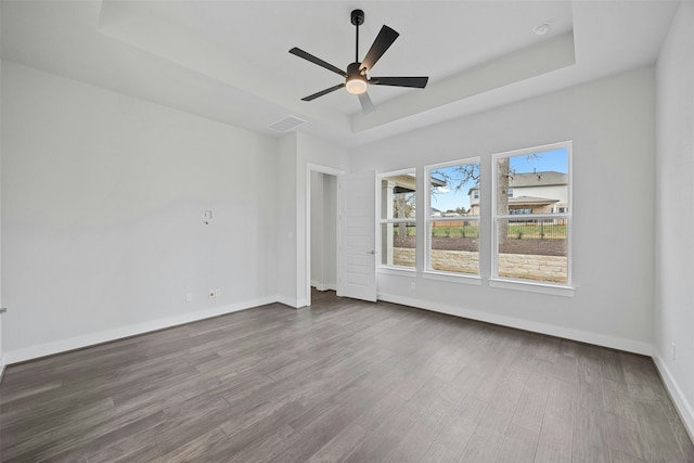 spare room with hardwood / wood-style floors, a tray ceiling, and ceiling fan