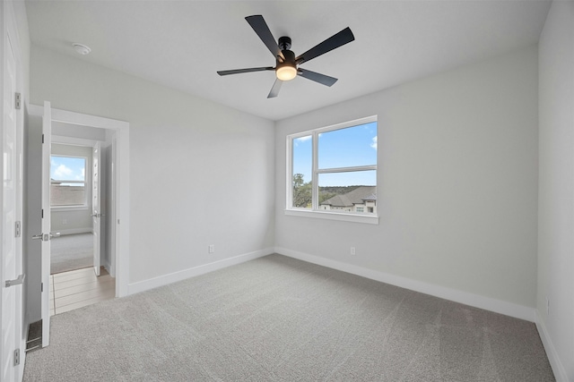 carpeted spare room featuring ceiling fan and a wealth of natural light