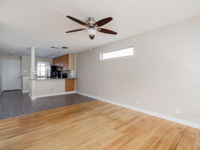 unfurnished living room featuring ceiling fan, sink, and wood-type flooring