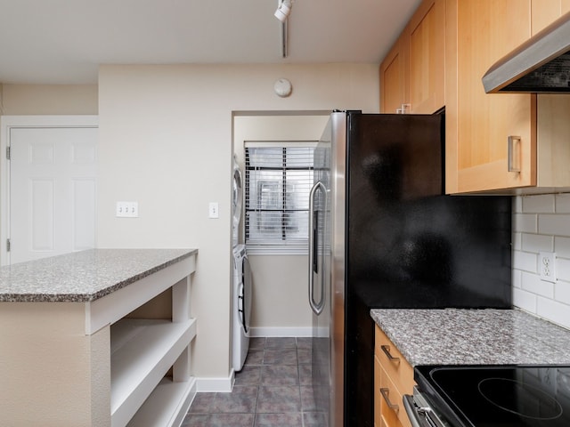 kitchen featuring stainless steel fridge, light brown cabinetry, tasteful backsplash, stacked washer / drying machine, and range hood