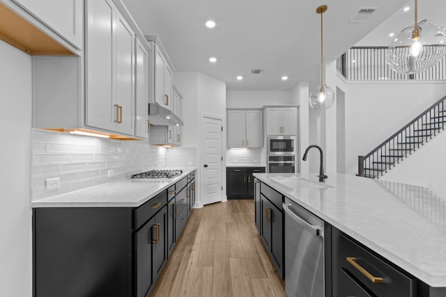 kitchen with white cabinetry, appliances with stainless steel finishes, hanging light fixtures, and light hardwood / wood-style floors