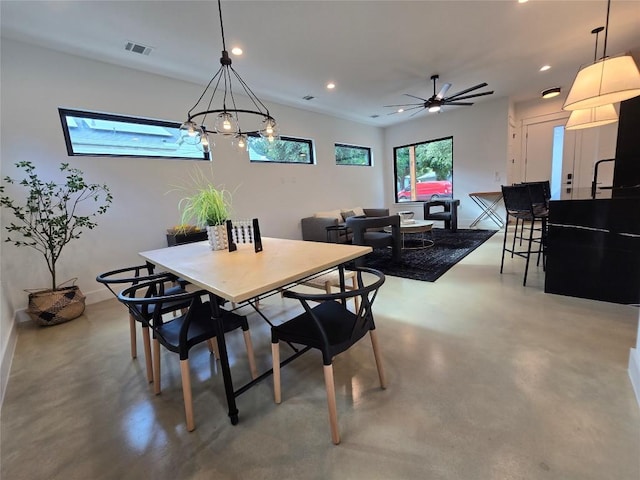 dining room featuring concrete flooring and ceiling fan with notable chandelier