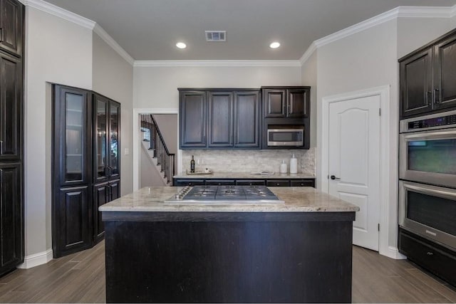 kitchen featuring backsplash, crown molding, a kitchen island, and stainless steel appliances