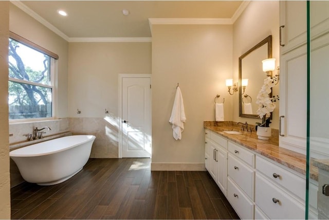 bathroom featuring vanity, wood-type flooring, a tub to relax in, and ornamental molding