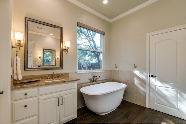 bathroom with vanity, crown molding, tile walls, and a bathing tub