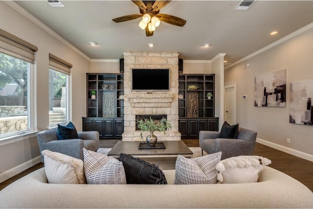 living room with ceiling fan, a stone fireplace, dark hardwood / wood-style flooring, and ornamental molding