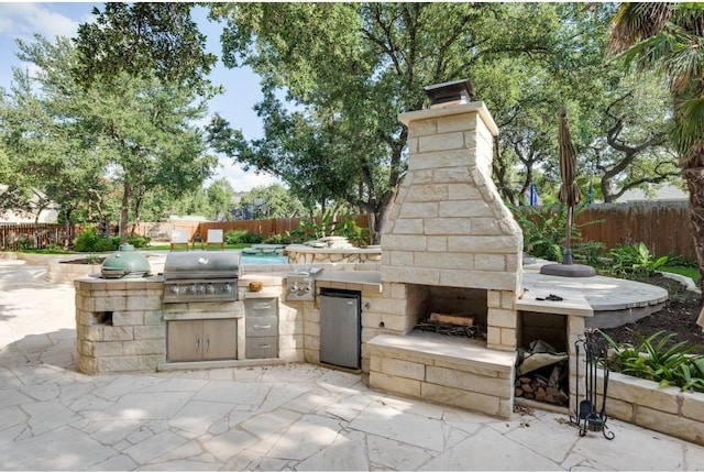 view of patio with an outdoor stone fireplace, grilling area, and an outdoor kitchen