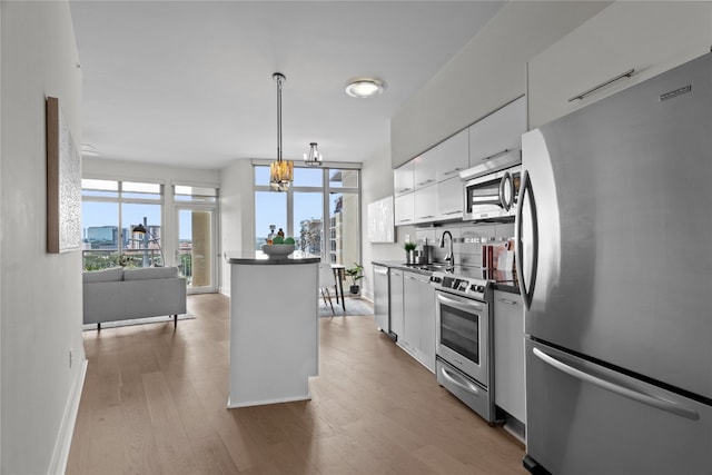 kitchen featuring wood-type flooring, hanging light fixtures, white cabinetry, stainless steel appliances, and a notable chandelier