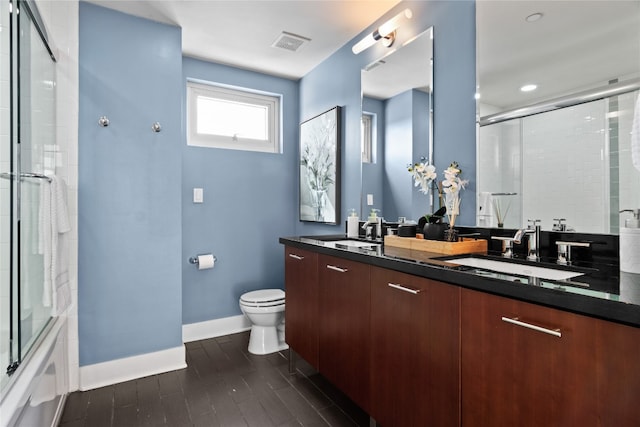 full bathroom featuring vanity, toilet, hardwood / wood-style flooring, and combined bath / shower with glass door