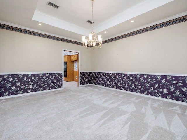 carpeted empty room with a notable chandelier, a tray ceiling, and crown molding