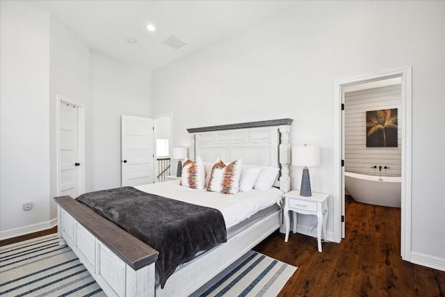 bedroom with a towering ceiling, dark hardwood / wood-style flooring, and ensuite bathroom