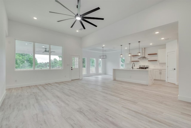 unfurnished living room with ceiling fan, light hardwood / wood-style floors, plenty of natural light, and sink