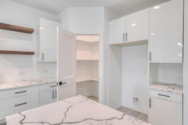 kitchen featuring light stone countertops, light hardwood / wood-style flooring, and white cabinetry