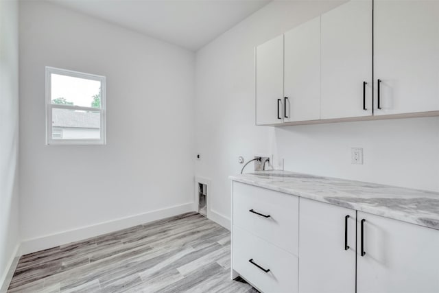 washroom featuring hookup for an electric dryer, hookup for a washing machine, cabinets, and light hardwood / wood-style floors