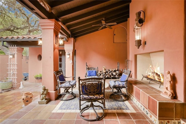view of patio / terrace featuring a ceiling fan and a lit fireplace