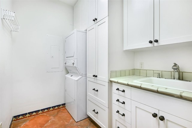 laundry room featuring stacked washer / dryer, cabinet space, light tile patterned flooring, and a sink