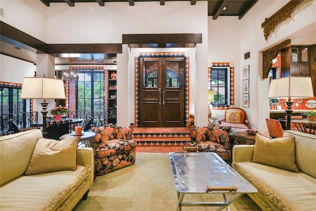 living room with a towering ceiling, a chandelier, and beamed ceiling