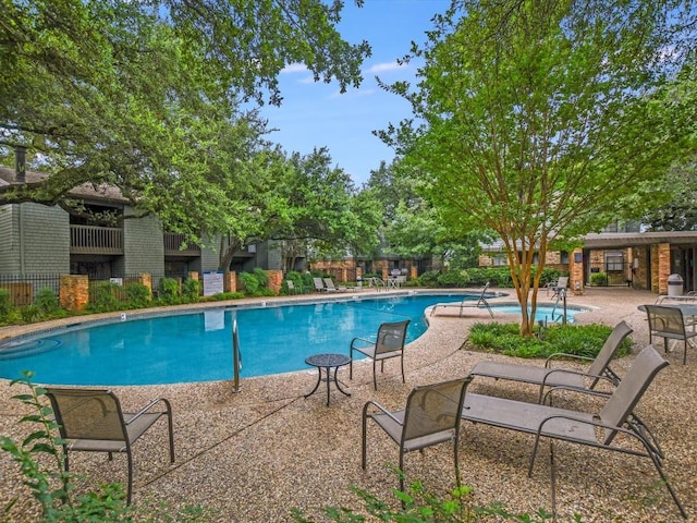 community pool with a patio and fence