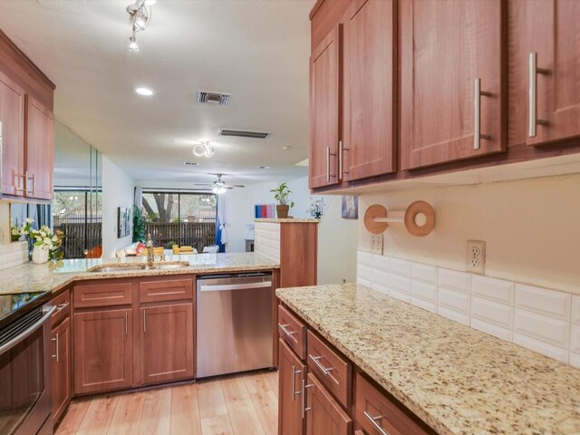 kitchen with light wood-type flooring, sink, kitchen peninsula, stainless steel appliances, and light stone countertops