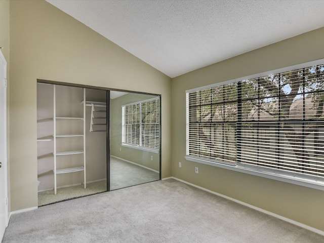 unfurnished bedroom with multiple windows, lofted ceiling, light colored carpet, and a closet