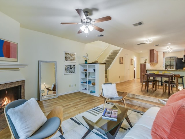 living room with light hardwood / wood-style floors, a fireplace, and ceiling fan