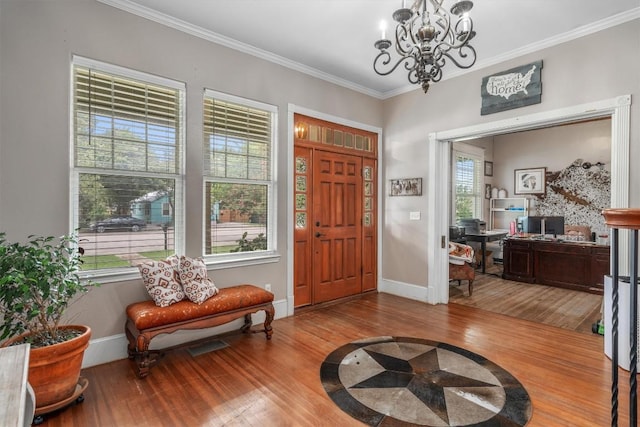 foyer entrance featuring hardwood / wood-style flooring, crown molding, and an inviting chandelier