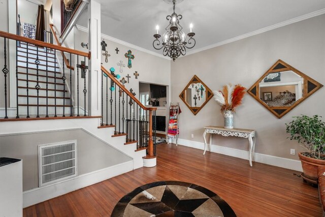 entryway with crown molding, wood-type flooring, and an inviting chandelier