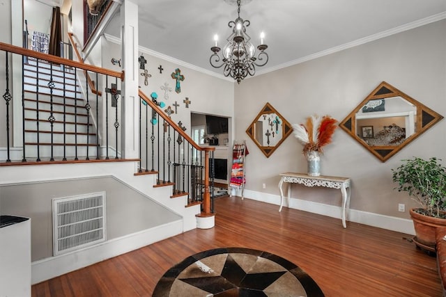 foyer featuring hardwood / wood-style flooring, ornamental molding, and a chandelier