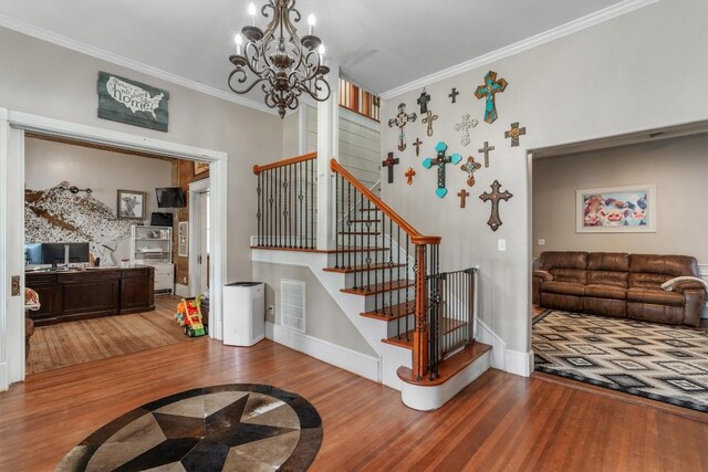 staircase with hardwood / wood-style flooring, ornamental molding, and a chandelier