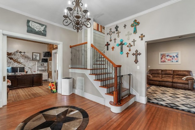 staircase with crown molding, hardwood / wood-style floors, and a notable chandelier