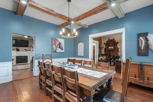 dining area with dark hardwood / wood-style flooring, beam ceiling, and a notable chandelier