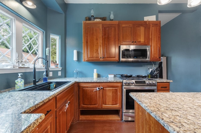 kitchen featuring light stone counters, stainless steel appliances, sink, and plenty of natural light