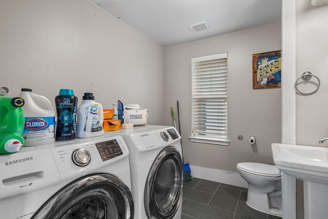 washroom featuring dark tile patterned flooring and washing machine and dryer