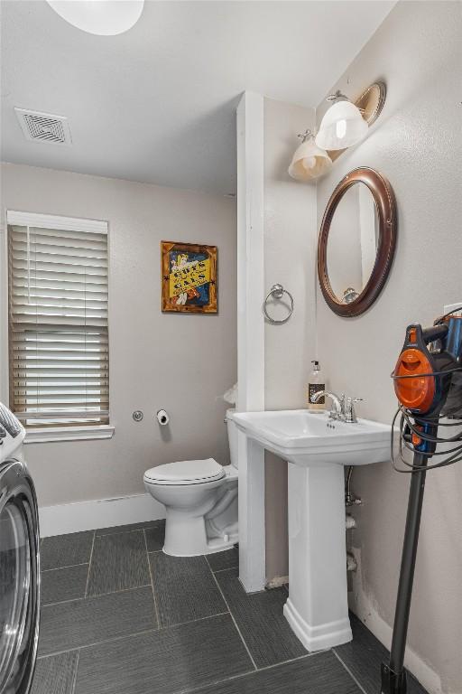 bathroom featuring washer / clothes dryer and toilet