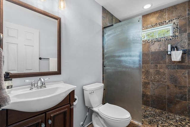 bathroom featuring vanity, toilet, and a tile shower