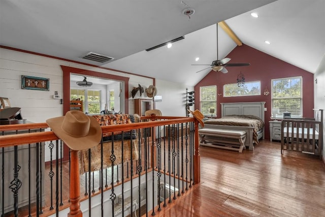 bedroom with wood-type flooring, lofted ceiling with beams, and multiple windows