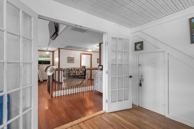 corridor featuring wood-type flooring, ornamental molding, and wooden ceiling