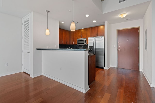 kitchen featuring kitchen peninsula, dark hardwood / wood-style floors, stainless steel appliances, and decorative light fixtures