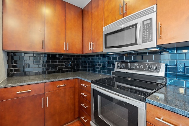 kitchen featuring stainless steel appliances, tasteful backsplash, and dark stone countertops