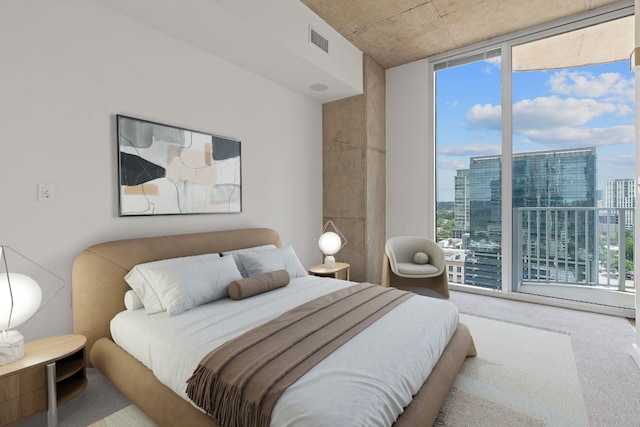 bedroom featuring multiple windows, light carpet, and expansive windows