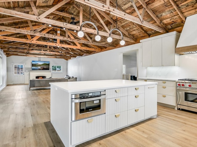 kitchen featuring wall oven, light hardwood / wood-style flooring, custom exhaust hood, vaulted ceiling with beams, and oven