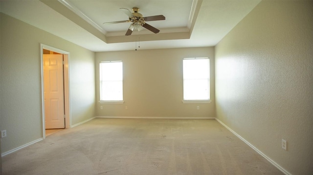 unfurnished room with ornamental molding, a healthy amount of sunlight, ceiling fan, and a tray ceiling