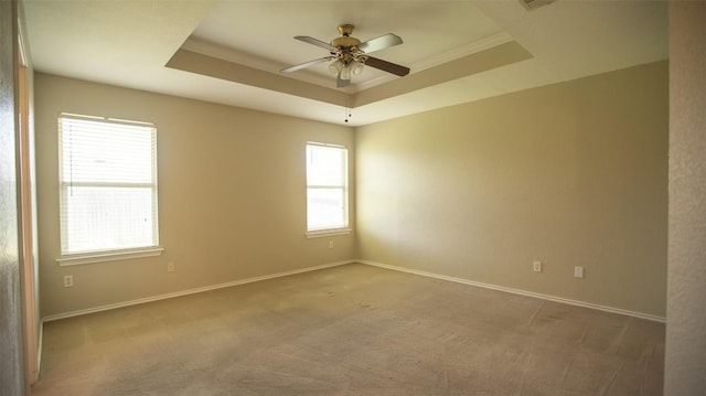 carpeted spare room with a tray ceiling, ornamental molding, and ceiling fan