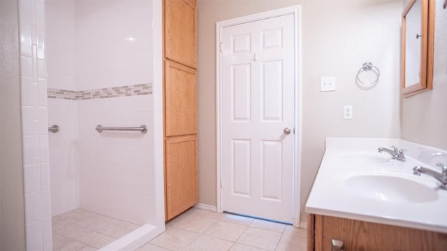 bathroom with tiled shower, vanity, and tile patterned flooring