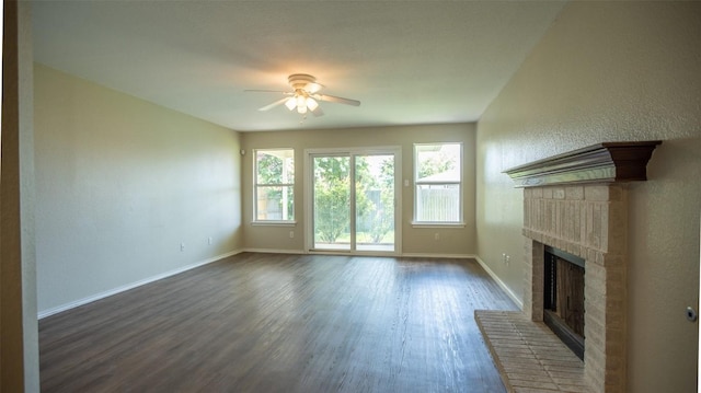 unfurnished living room with ceiling fan, dark wood-type flooring, and a brick fireplace