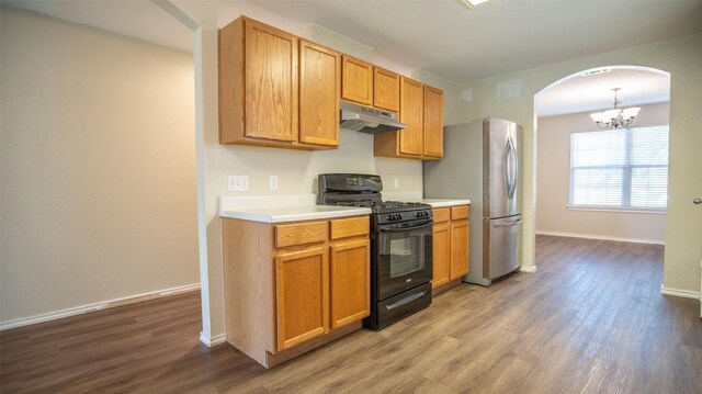 kitchen with stainless steel fridge, gas stove, hardwood / wood-style flooring, and an inviting chandelier