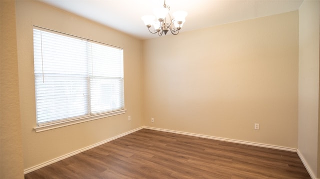 empty room featuring dark hardwood / wood-style floors and an inviting chandelier